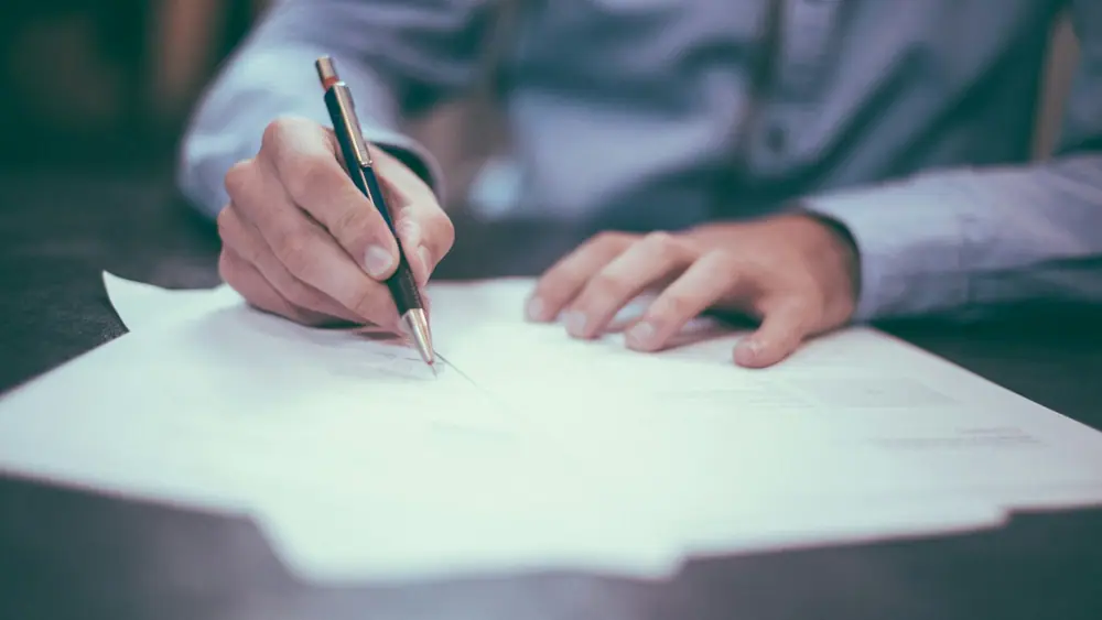 Una persona firma un documento en papel con un bolígrafo