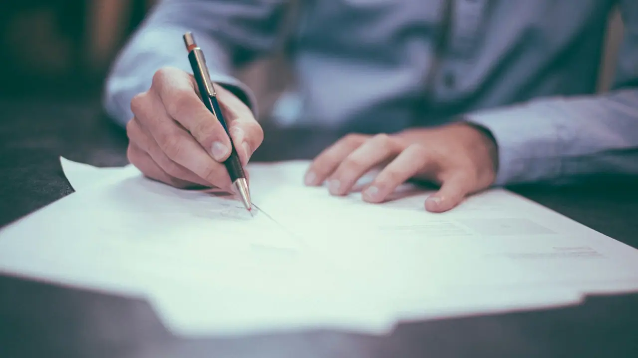 Una persona firma un documento en papel con un bolígrafo