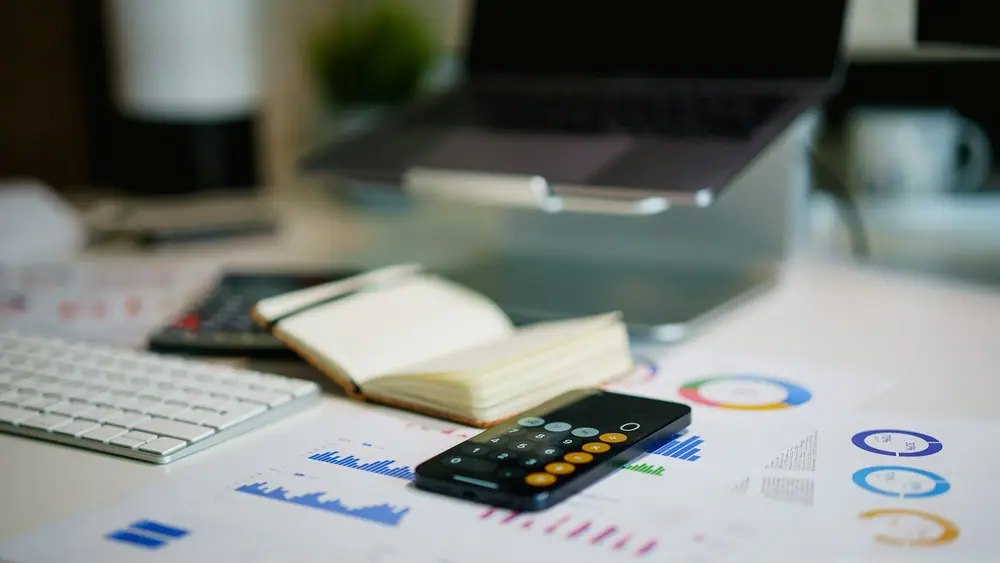 Mesa de oficina con informes financieros, gráficos, calculadora y teclado