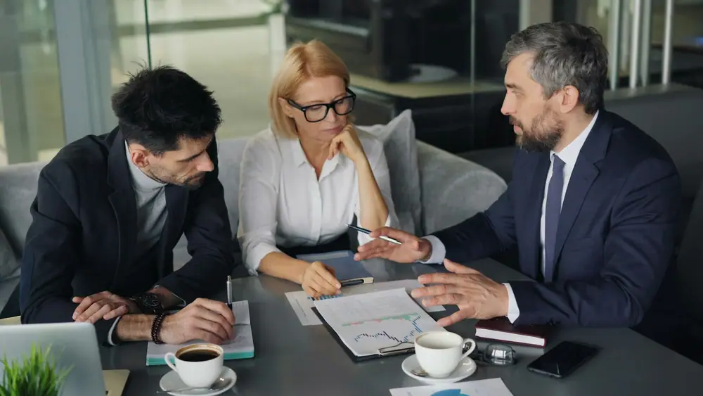 Tres profesionales revisan documentos en una reunión