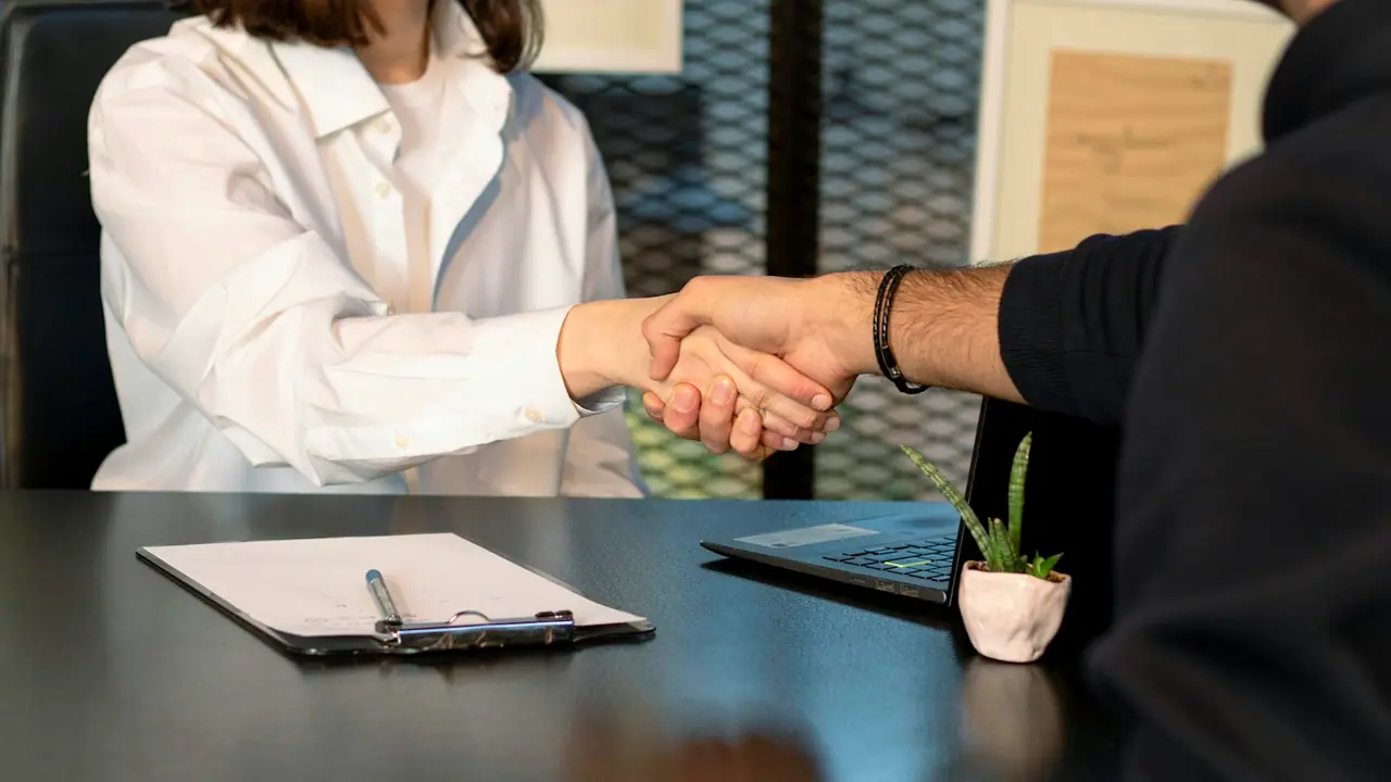 Un hombre y una mujer se dan la mano en una reunión de trabajo